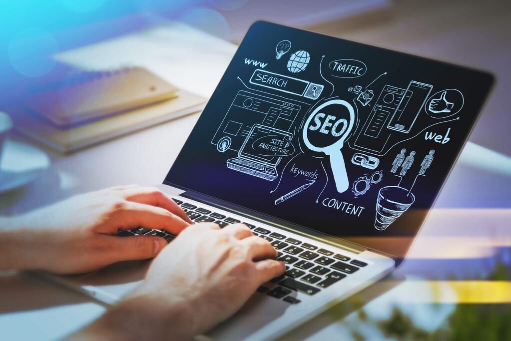 SEO consultant working on laptop with site architecture, keyword research, traffic and content concept icons — Dubai UAE